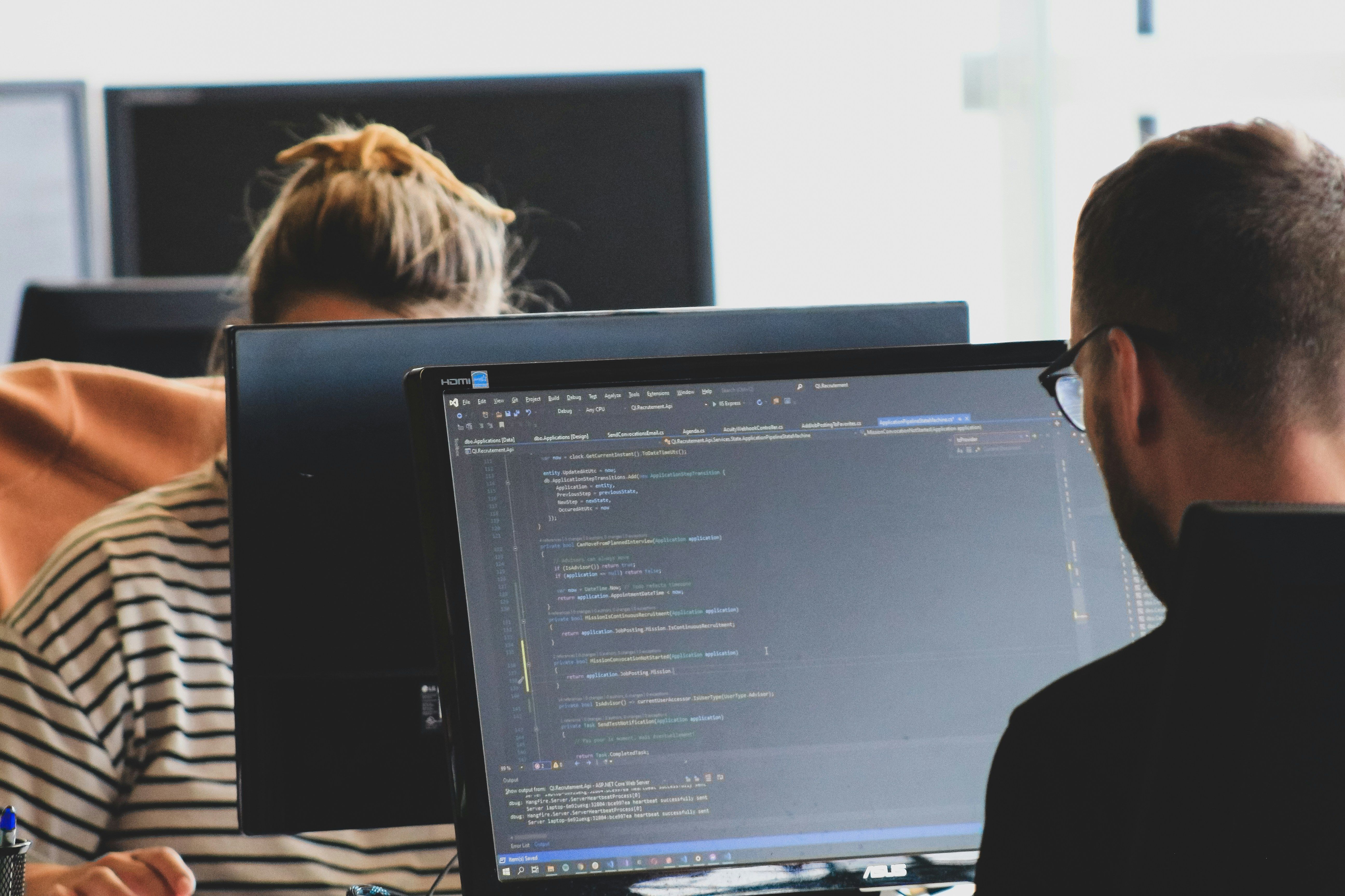 a man and a woman are sitting in front of a computer screen .